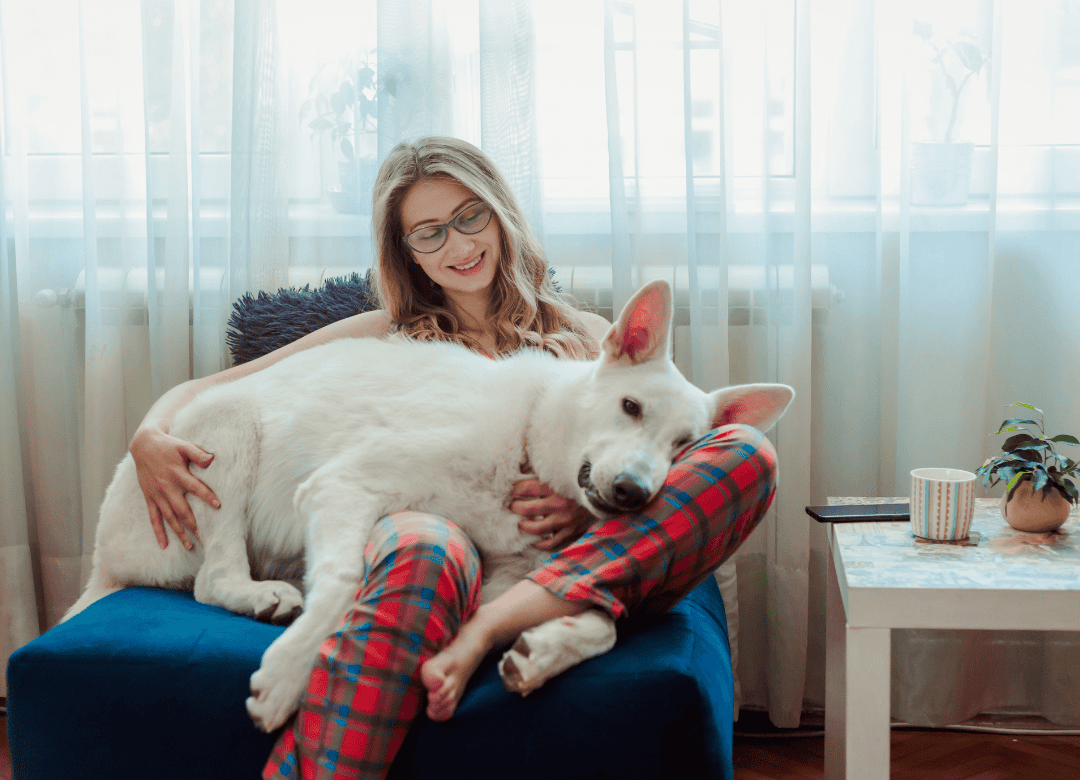 A woman in PJs cuddles her pup as a way to say to her dog happy Valentine's Day.