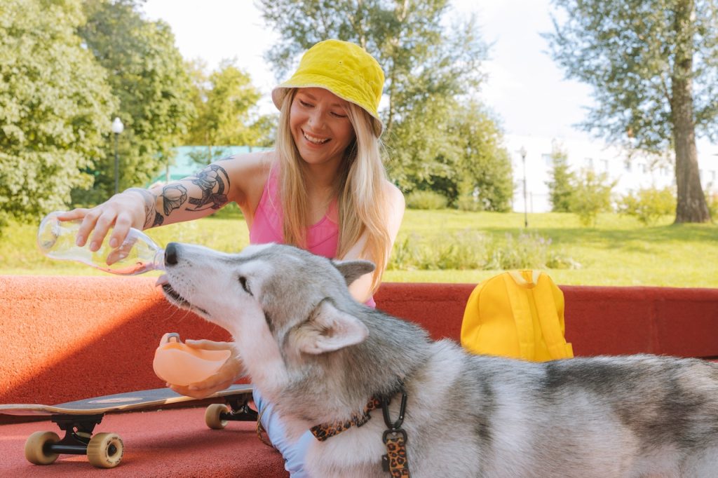 a woman share water with her husky because she knows it's important for when a dog needs water.