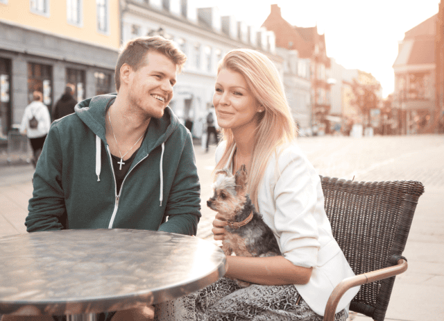 a couple and their pup enjoy an outdoor cafe