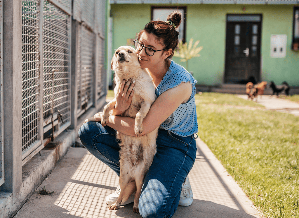 a woman hugs a dog at a dog shelt